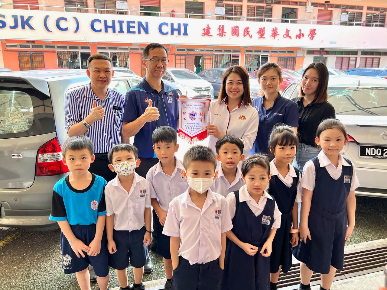 ■建集华小副校长林国彪(后排左二)移交感谢锦旗给廖彩彤(后排中)。