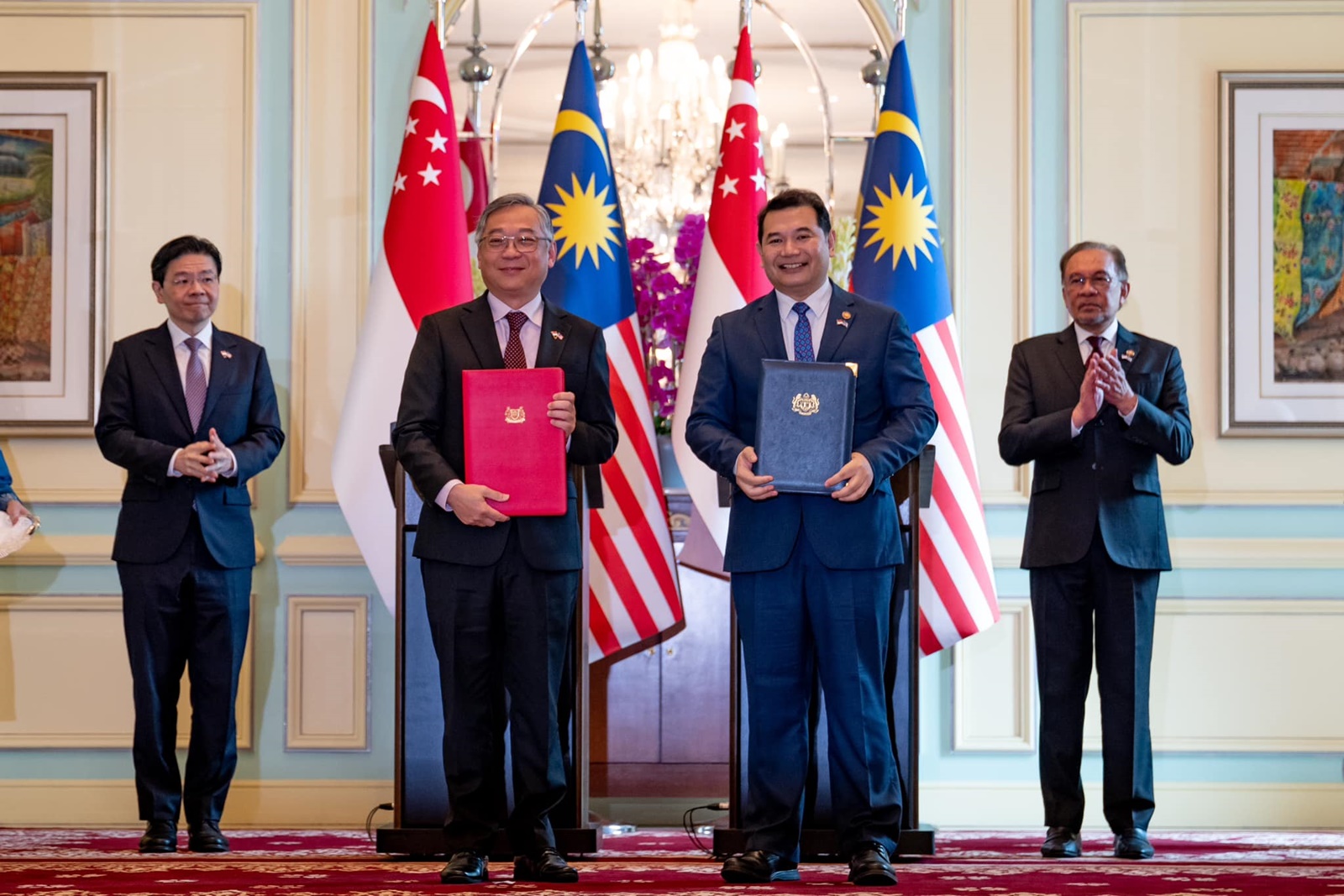 ■在黄循财（左）和安华（右） 见证下，两国代表颜金勇（左2）、拉菲兹交换柔新经济特区协议。（图：首相安华面子书）